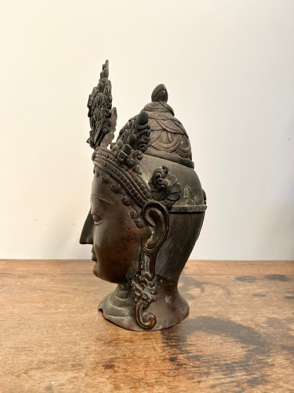 Decorative Tara statue of a face with intricate carvings on a wooden surface.