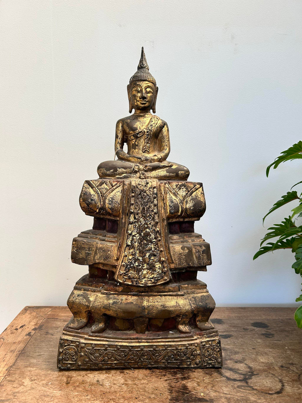 Bronze Buddha statue on a wooden surface with a white background
