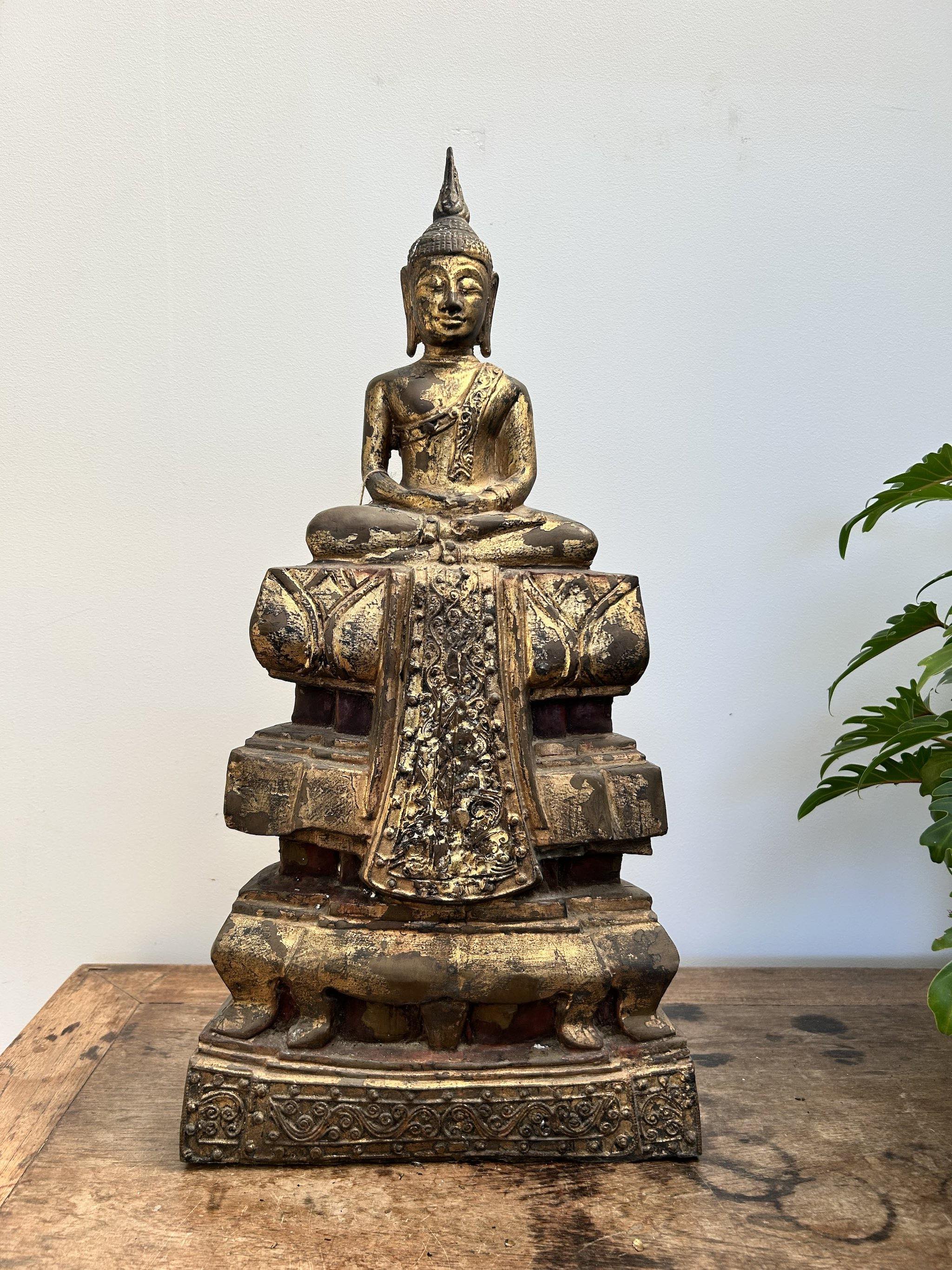 Bronze Buddha statue on a wooden surface with a white background