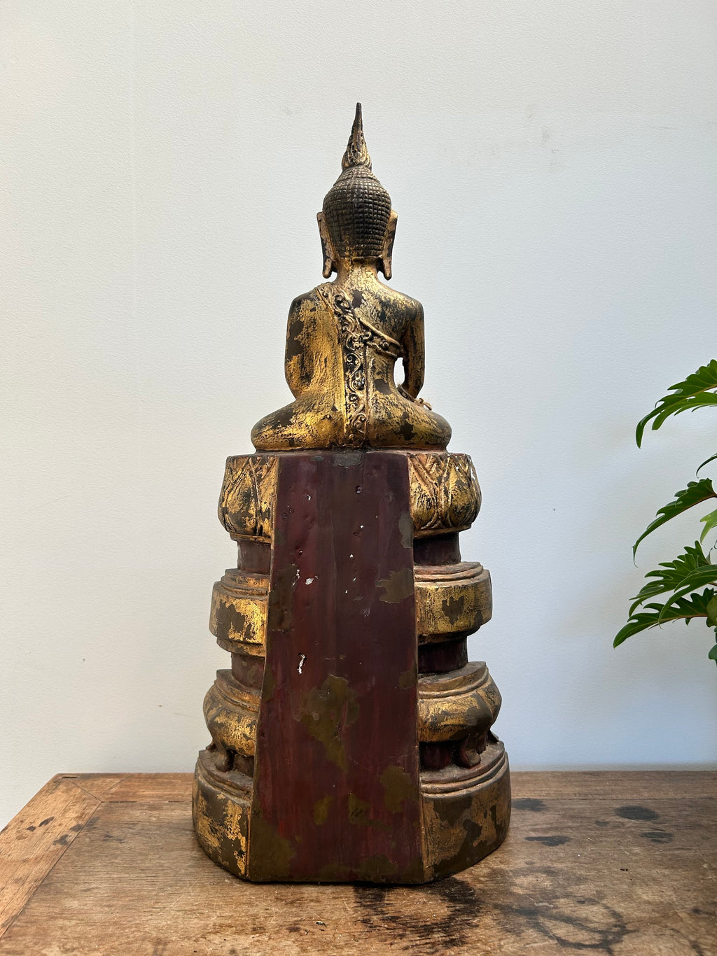 Bronze Buddha statue on a wooden surface with a white background