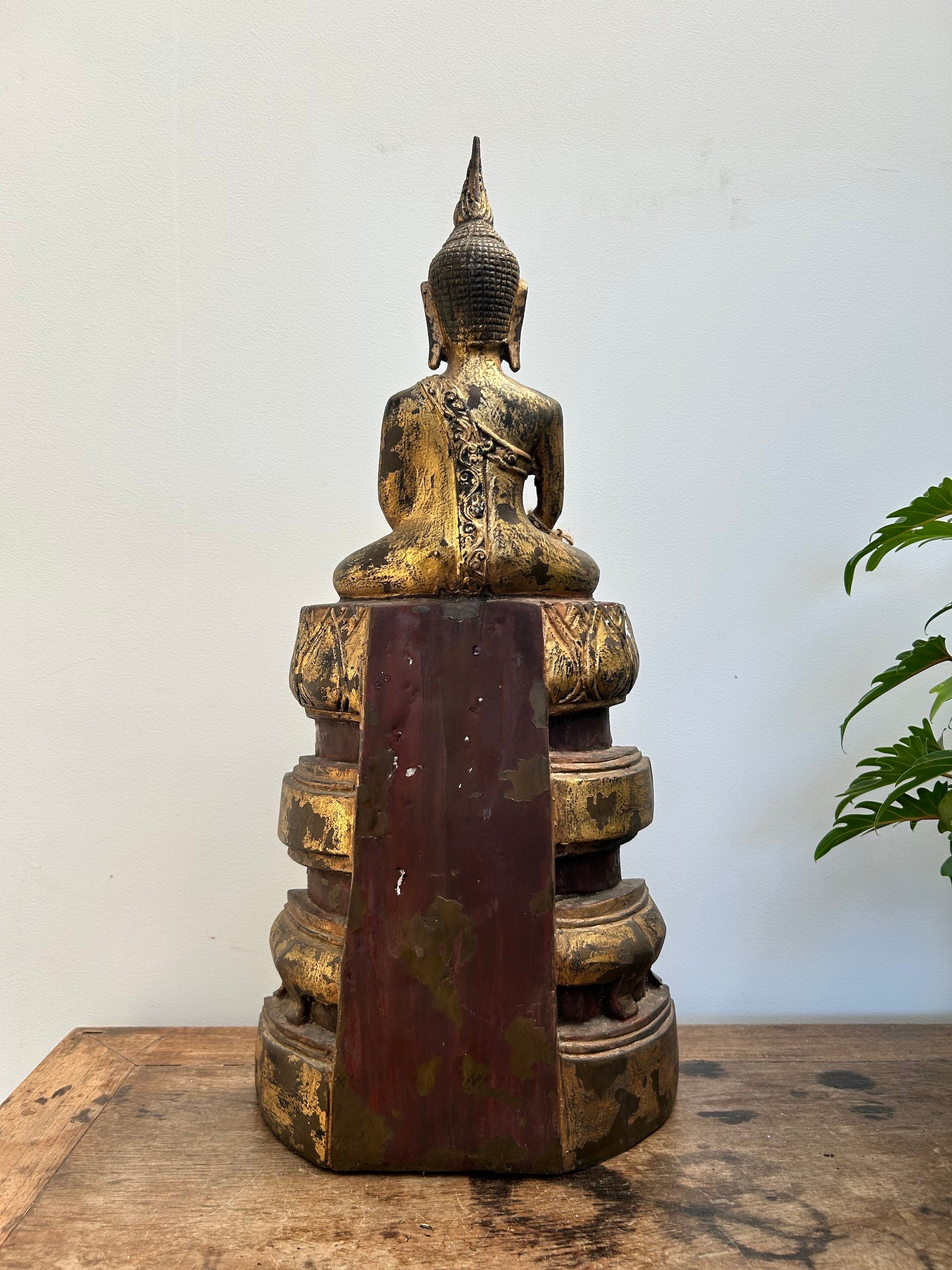 Bronze Buddha statue on a wooden surface with a white background
